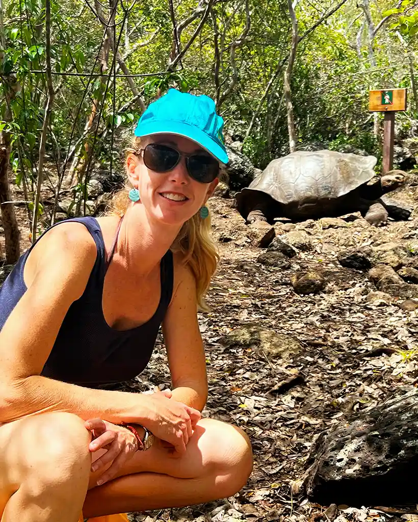 Carolina encountering a giant tortoise in the Galápagos Islands Carolina sitting on a forest trail near a giant tortoise in the Galápagos