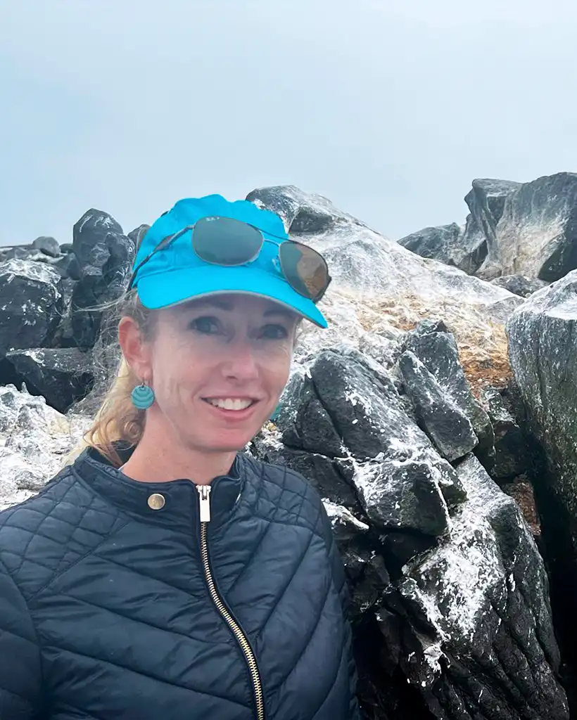 Carolina exploring the rocky coastline of the Galápagos Islands Carolina standing on volcanic rocks along the Galápagos coastline