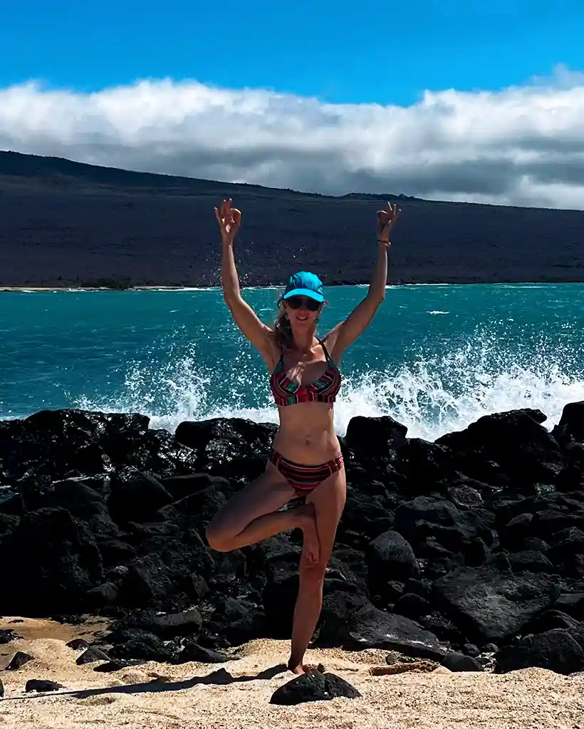 Carolina practicing yoga on a volcanic beach in the Galápagos Carolina practicing a yoga pose on a volcanic beach with turquoise water in the Galápagos
